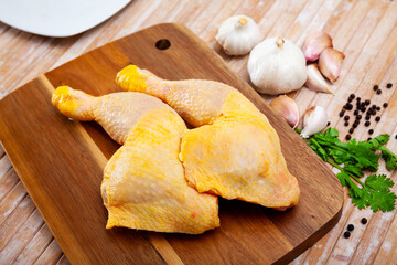 Fototapeta premium Raw chicken legs on cutting board and plate