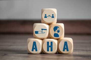 Cubes and dice with hygiene icons covid-19 corona virus and the german acronym for AHA - Abstand, Hygiene, Alltagsmaske on wooden background