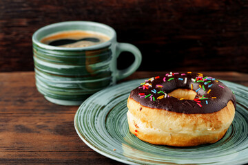 Glazed donut on green plate with cup of coffee