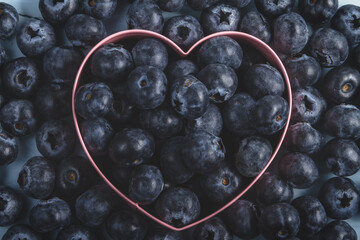 Blueberry heart.
Metallic heart-shaped mold filled with blueberries on a background made up of more blueberries.