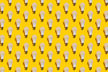 Pattern of white energy saving light bulbs on a yellow background.