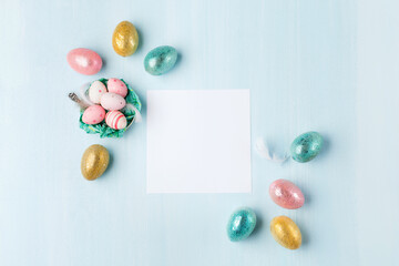 Easter greeting card with colorful easter eggs on blue background. Top view, flat lay with space for your text.