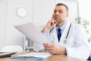 Portrait of mature doctor reading medical report