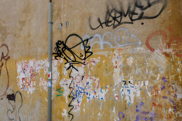 Graffiti on a yellow wall with a drainpipe 