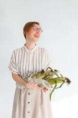 Young pretty girl on a gray background holding corn cobs in her hands