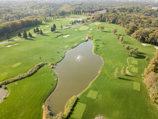 Aerial drone view. Lake with a fountain among a green golf course