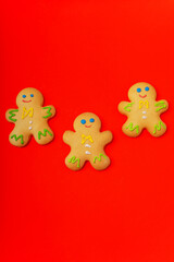 Three gingerbread men are located on a red background. Flat lay. New Year and Christmas concept. There is a place for text