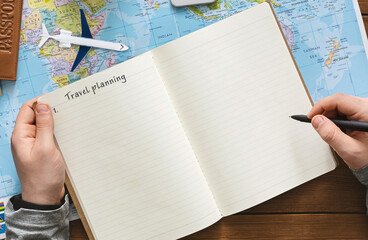 Travel Planning Concept. Man taking notes to notepad over world map background