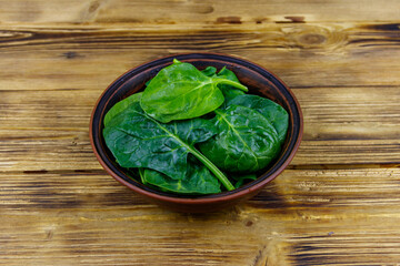 Fresh green spinach leaves in bowl on a wooden table
