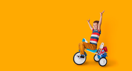 Happy boy on tricycle carry a lot of gifts on yellow background.