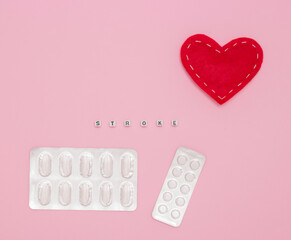 Concept of health, cardiology, heart disease. Words STROKE on white cubes, tablets in blisters on a...