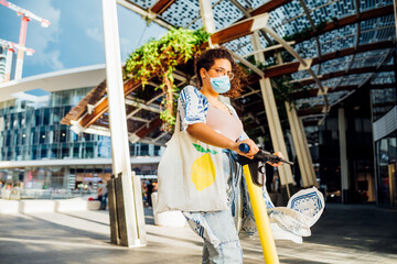 Young mixed woman riding electric scooter outdoors - Woman enjoying new electric mobility using kick scooter