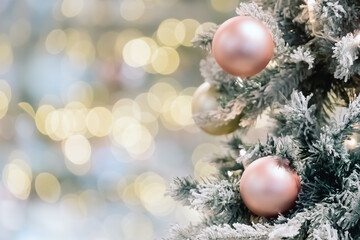 Decorated and illuminated christmas tree on blur bokeh background. Golden baubles on fir tree branch with defocused lights on backdrop. Happy new year or merry christmas postcard. Banner. Copy space