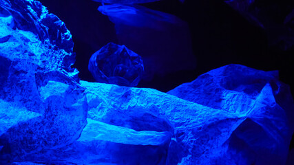 Old pieces of plastic floating deep in the ocean, in water isolated on black.