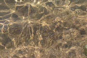 Clear sea waters over a sandy bottom in the sunlight background texture. Copy space.