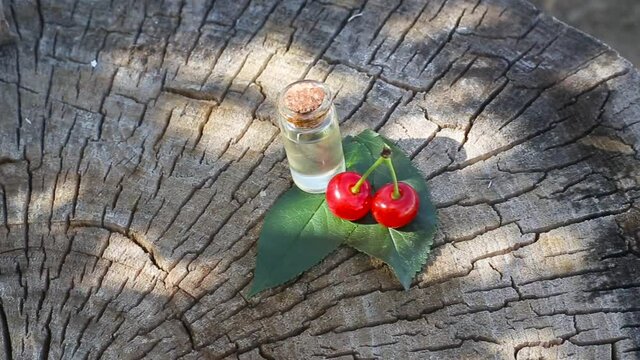 Bottle with cherry oil on a wooden background. The concept of cherry aromatic oils in therapy and cosmetology, copy space
