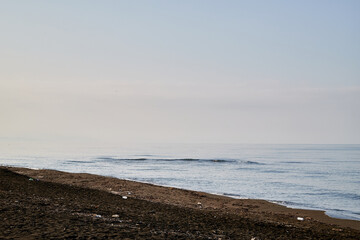 View from sand beach to water of sea and small waves in a nice day or evening with blues sky and bright sun. The concept of a holiday on the sea or ocean in the South.