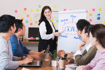 Young smart asian business female leader in a casual meeting with her teamwork colleagues at the modern design office presenting sales strategy plan and data or forecast for a project goal schedule