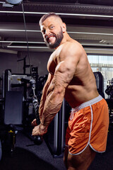 Fototapeta na wymiar Handsome male bodybuilder in gym. Big strong man during training in the gym. Guy with big muscles who is an athlete, trainer or instructor
