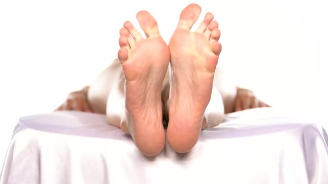 bare feet of a woman lying on a bed and relaxing on a white background