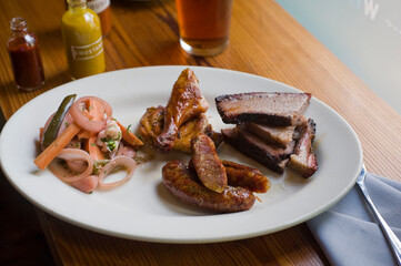 Barbecue catering platter with variety of meats. Traditional Texas BBQ: Beef brisket, beef ribs, pork ribs, sausage links, black pepper roasted chicken, and turkey served with homemade sauce.