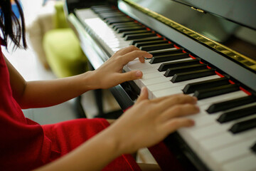 Obraz premium Hands of young musician playing upright piano at home during online class, social distance during quarantine, self-isolation, online education concept.Female Asian fingers play instrument.