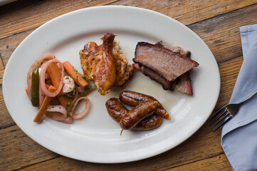 Barbecue catering platter with variety of meats. Traditional Texas BBQ: Beef brisket, beef ribs, pork ribs, sausage links, black pepper roasted chicken, and turkey served with homemade sauce.