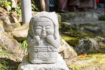 Fototapeta na wymiar A small stone statue enshrined on a mountain path in the countryside