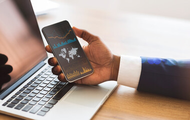 Black businessman checking global financial analytic on smartphone or trading on forex