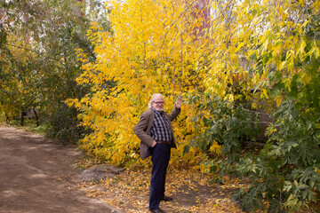 elegantly dressed grandfather walking in the autumn forest