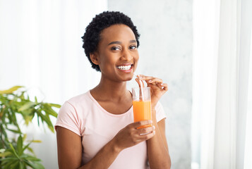 Healthy eating, dieting and detox. Pretty African American woman drinking fresh orange juice at...