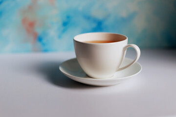 White cup of tea and saucer on blue background.Blue coffee cup on the white table over blue grunge background