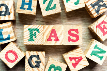Alphabet letter block in word FAS (abbreviation of Free alongside) with another on wood background