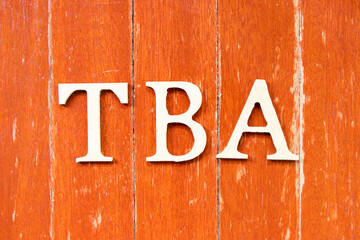 Alphabet letter in word TBA (abbreviation of to be announced) on old red color wood plate background
