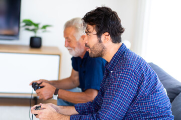 Fototapeta premium Father and son family time together at home concept. Happy father and son enjoy playing video games with joysticks in living room at home