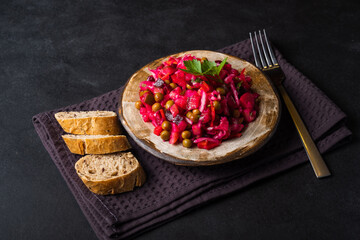 Vegetarian vegetable vinigret in a round clay plate on a dark background with copy space