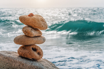 Balanced pebble pyramid on the beach on a sunny day. Sea foam on the background. Selective focus....