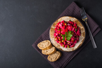 Vegetarian vegetable vinigret in a round clay plate on a dark background with copy space