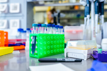 Transparent plastic test tubes in a green plastic stand, biochemistry laboratory environment, science background