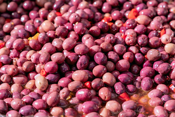 Red pickled olives with red peppers at a grocery market in italy
