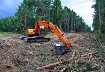 Excavator clearing forest for new development. Orange Backhoe modified for forestry work. Tracked heavy power machinery for forest and peat industry. Logging, road construction in forests