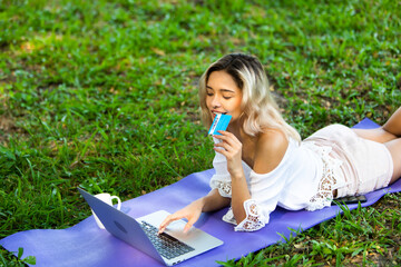 Online shopping, e-commerce. Young caucasian woman hands holding credit card and using tablet for online shopping in green park.