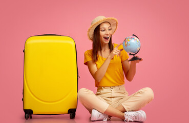 Emotional woman with globe sitting next to luggage
