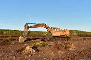 Fototapeta na wymiar Excavator digging drainage ditch in peat extraction site. Drainage of peat bogs and destruction of trees. Drilling on bog for oil exploration. Mining peatlands. Wetlands declining 