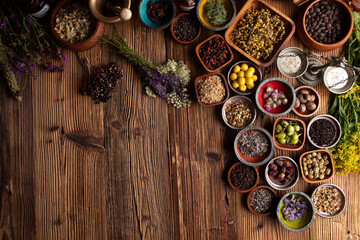 Natural medicine theme. Assorted dry herbs in bowls and brass mortar on rustic wooden table.