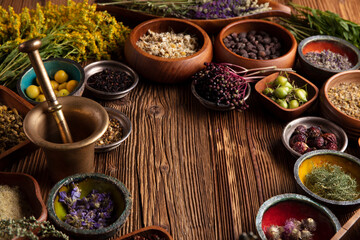 Obraz na płótnie Canvas Natural medicine theme. Assorted dry herbs in bowls and brass mortar on rustic wooden table.