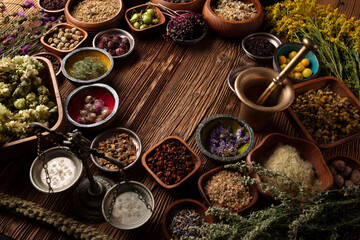 Natural medicine theme. Assorted dry herbs in bowls and brass mortar on rustic wooden table.