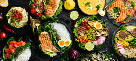 Food background: pasta, chicken, pumpkin, salad, meat, mushrooms, vegetables. On a black stone...