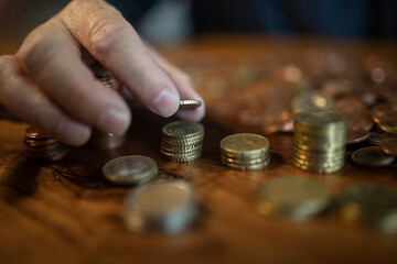 Hand und Geld, Mann zählt zuhause sein Kleingeld und baut Türme mit den Münzen