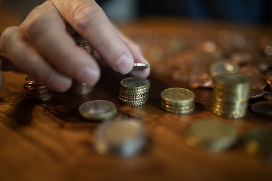 Hand und Geld, Mann zählt zuhause sein Kleingeld und baut Türme mit den Münzen